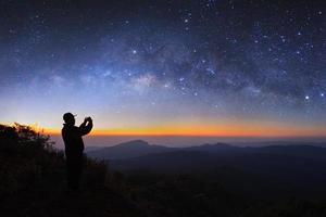 un hombre toma una foto de la galaxia de la vía láctea en doi inthanon chiang mai, tailandia. fotografía de larga exposición. con grano