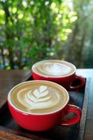 two latte art coffee in red cup photo