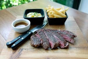 Grilled beef steak on cutting board and with pepper sauce photo