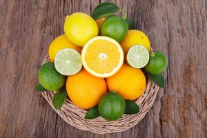 Mix of fresh citrus fruits in basket on wood photo