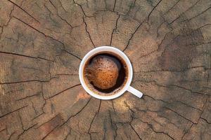 A cup of coffee on old tree stump texture background photo