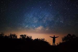 galaxia de la vía láctea y silueta de un hombre feliz de pie en la alta montaña doi luang chiang dao en la provincia de chiang mai, tailandia. foto