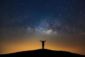 Milky way galaxy with stars and silhouette of a standing happy man, Long exposure photograph, with grain. photo