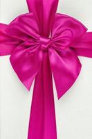 Pink ribbon with bow as gift on white background photo