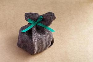 bolsa de regalo de saco con lazo de cinta sobre fondo marrón foto