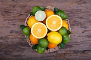 Mix of fresh citrus fruits in basket on wood photo