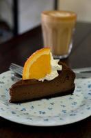 Chocolate cake with orange and latte coffee on wood table photo