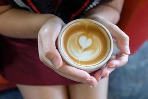 woman holding hot cup of latte coffee photo