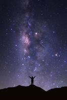 Milky way galaxy with stars and space dust in the universeand and silhouette of a standing happy man photo