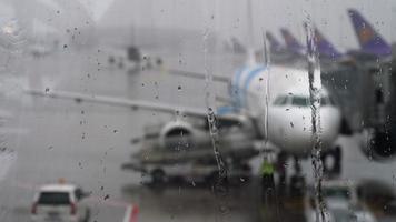 tormenta en el aeropuerto. vista del avión a través de gotas de lluvia y arroyos. temas de clima y retraso o vuelo cancelado. video