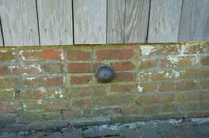 small iron cannonball stuck in side of brick building photo