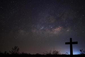 Silhouette of cross over milky way background,Long exposure photograph photo