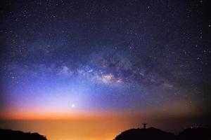 milky way galaxy and silhouette of a standing happy man on Doi Luang Chiang Dao high mountain in Chiang Mai Province, Thailand. photo