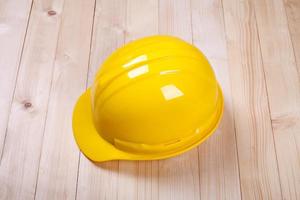 yellow hardhat architect on brown wood background photo