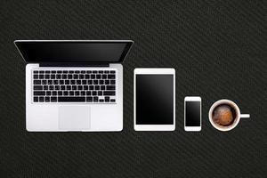 Laptop tablet smartphone  and coffee on black rubber  background with text space and copy space photo