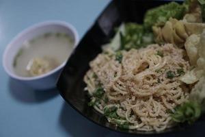 un tazón de fideos wonton originales y un tazón pequeño de albóndigas indonesias foto