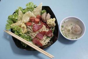 un tazón de fideos wonton más carne ahumada y un tazón pequeño de albóndigas foto