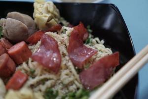 un tazón de fideos wonton más carne ahumada y un tazón pequeño de albóndigas foto