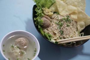 un tazón de fideos wonton originales y un tazón pequeño de albóndigas indonesias foto