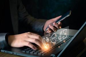 Concept of business communication. Businessman using computer and smartphone to contact customers via online internet, meeting, global network, shape icon phone email mail message on virtual screen. photo
