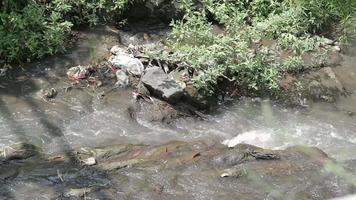 la rivière coule entre les gros rochers qui embellissent la rivière même s'il y a des déchets video