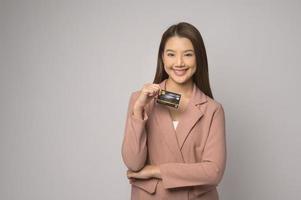 Young asian woman holding credit card over white background studio, shopping and finance concept. photo