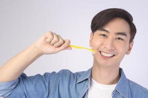 joven sonriente sosteniendo cepillo de dientes sobre estudio de fondo blanco, salud dental y concepto de ortodoncia. foto