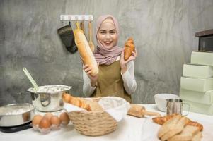joven hermosa mujer musulmana está horneando en su negocio de cocina, panadería y cafetería foto