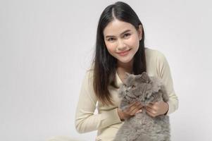 una mujer joven está sosteniendo un gato adorable, jugando con un gato en un estudio de fondo blanco foto