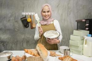 joven hermosa mujer musulmana está horneando en su negocio de cocina, panadería y cafetería foto