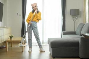 joven mujer feliz trapeando y aspirando el piso en la sala de estar. foto