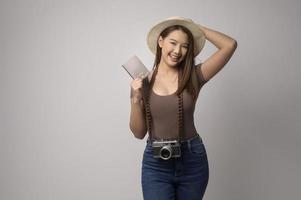 Young happy asian tourist woman over white background studio, travel and holidays concept. photo