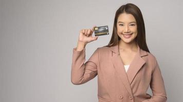 Young asian woman holding credit card over white background studio, shopping and finance concept. photo