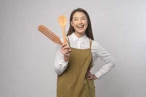 Portrait of young asian woman wearing apron over white background studio, cooking and entrepreneur concept photo
