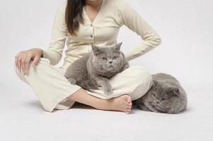 una mujer joven está sosteniendo un gato adorable, jugando con un gato en un estudio de fondo blanco foto