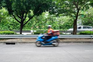 Courier or delivery man on motorbike moving fast, blurred motion. Courier carries out orders for delivery in urban area. photo