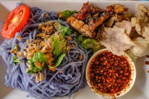 Blue pea Noodle Served Spicy sauce and pork meat top up with Green Vagatable photo