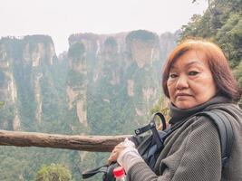 Portrait photo of Senior asian women with Beautiful mountain of Yuanjiajie or Avartar mountain at Zhangjiajie National Forest Park in Wulingyuan District Zhangjiajie City China