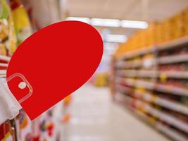 maqueta de etiqueta de descuento roja en blanco en los estantes de productos en el supermercado foto