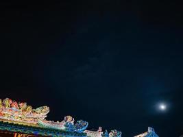 techo del templo chino bajo el cielo nocturno en la ciudad de bangkok, tailandia foto