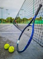 Tennis racket and tennis balls on tennis hard court. photo