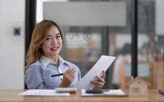 retrato de una hermosa y sonriente mujer asiática de negocios que trabaja en un escritorio de oficina moderno usando una computadora portátil, empleados de negocios, concepto de telemarketing de comercio electrónico de marketing en línea independiente. foto