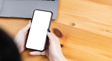 hand woman using a telephone, empty screen smart phone and computer on wooden table top view. photo