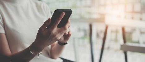 cierre de las manos de una mujer de negocios usando, tocando la pantalla de un teléfono inteligente móvil mientras trabaja en una computadora portátil en el escritorio de la oficina en casa, comercio electrónico, concepto de tecnología de Internet foto