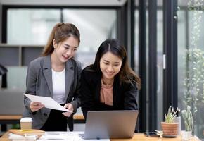 Two Young Asian businesswoman discuss with new startup project Idea presentation, analyze planning and financial statistics and investment market at office. photo