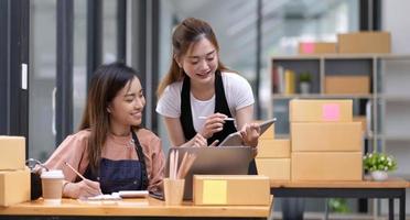 Portrait of Starting small businesses SME owners, two Asian woman check online orders Selling products working with boxs freelance work at home office, sme business online small medium enterprise photo