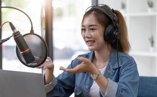 Beautiful asian young woman radio host working, setting microphone, preparing to speak before recording podcast and live on social media. Technology of on-air online in broadcasting at home studio. photo