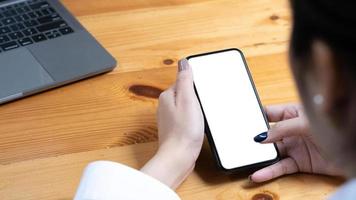 hand woman using a telephone, empty screen smart phone and computer on wooden table top view. photo