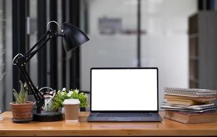 Front view computer laptop with empty screen, coffee cup, pencil holder, notebook and house plant on wooden table. photo