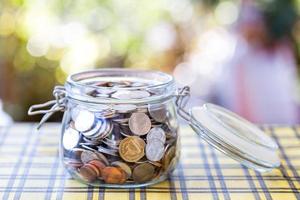 Many coins in glass jar, saving. photo